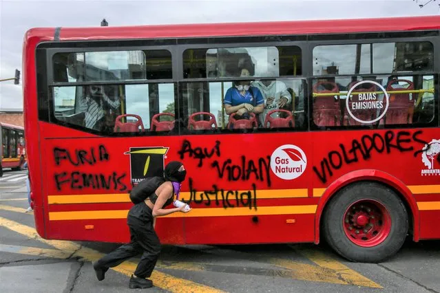 A demonstrator draws graffiti on a bus during a protest against the alleged sexual abuse of an underage woman inside a Transmilenio public transport station, in Bogota, Colombia on November 3, 2022. (Photo by Andrea Ariza/AFP Photo)