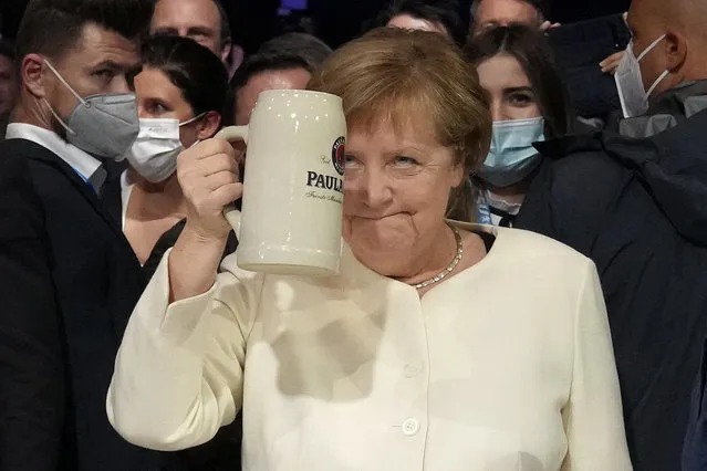 German chancellor Angela Merkel salutes with a beer mug during a state election campaign in Munich, Germany, Friday, September 24, 2021 two days before the General election on Sunday, Sept. 26, 2021. (Photo by Matthias Schrader/AP Photo)
