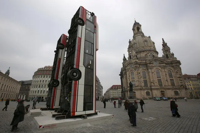 People walk next to the art instalation “Monument” by Syrian artist Manaf Halbouni, made from three passenger busses in Dresden, Germany February 8, 2017. (Photo by Matthias Schumann/Reuters)