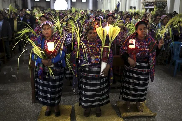 Indigenous women hold traditional palm and candles during the Catholic Palm Sunday procession inside a church in San Pedro Sacatepequez, Guatemala, March 20, 2016. (Photo by Saul Martinez/Reuters)