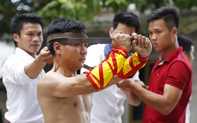 Dang Tien Duy (front), 28, bends a metal bar around his head as he performs during a showcase of the traditional Thien Mon Dao kung fu at Du Xa Thuong village, southeast of Hanoi, Vietnam May 10, 2015. (Photo by Reuters/Kham)