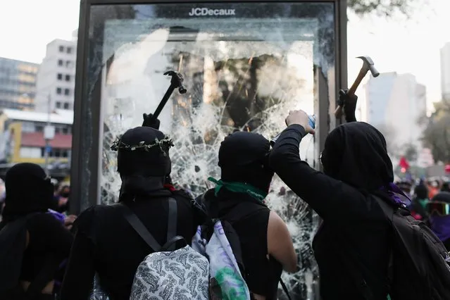 Demonstrators smash a billboard during a protest to mark the International Day for the Elimination of Violence Against Women, in Mexico City, Mexico on November 25, 2021. (Photo by Raquel Cunha/Reuters)