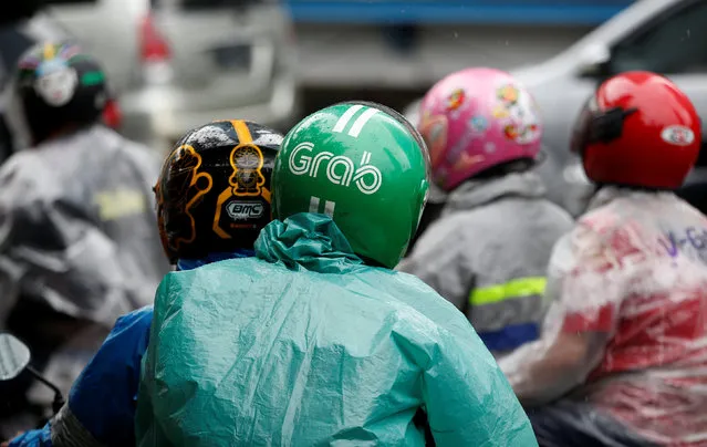 A passenger wears a helmet from the motorbike ride-hailing service Grab on a street in Jakrta, Indonesia, February 1, 2017. (Photo by Darren Whiteside/Reuters)