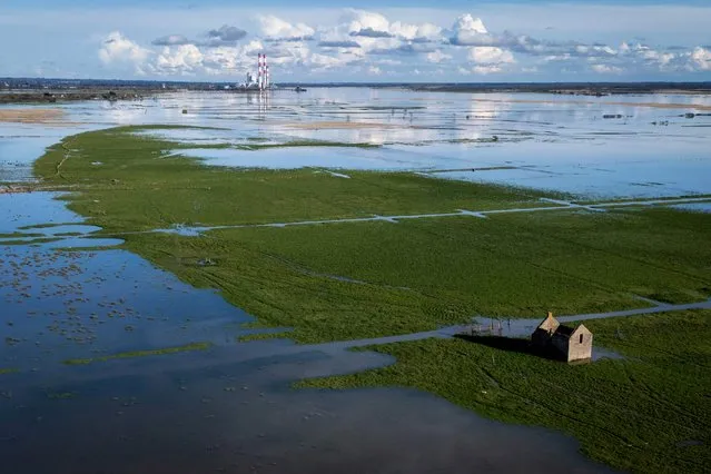 This photograph taken on March 10, 2024, shows a view of the coal powerplant of Cordemais (in the background) and a flooden field, due to large equinox tide, in Lavau-sur-Loire. (Photo by Loic Venance/AFP Photo)