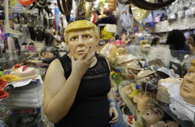In this Tuesday, January 31, 2017 photo, a woman jokingly tries on a mask in the likeness of U.S. President Donald Trump inside a costume store in Sao Paulo, as Brazilian gear up for Carnival. According to the store manager, the new face of the White House is the hottest mask for this year's party. (Photo by Andre Penner/AP Photo)