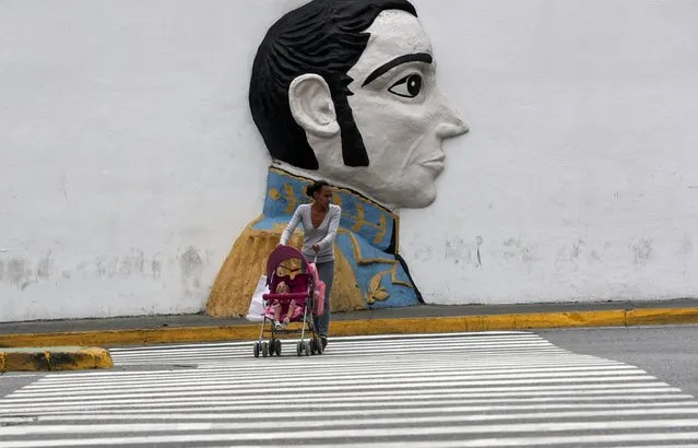 A pedestrian looks to cross an avenue backdropped by a wall relief of Venezuelan hero Simon Bolivar, just outside of the Supreme Court building, in Caracas, Venezuela, Wednesday, May 8, 2019. Supreme Court Justice Moreno spoke Wednesday following U.S. Vice President Mike Pence's remarks that the U.S. would extend sanctions to all members of the Venezuelan court if they continue to be a “political tool” of President Nicolás Maduro. (Photo by Martin Mejia/AP Photo)