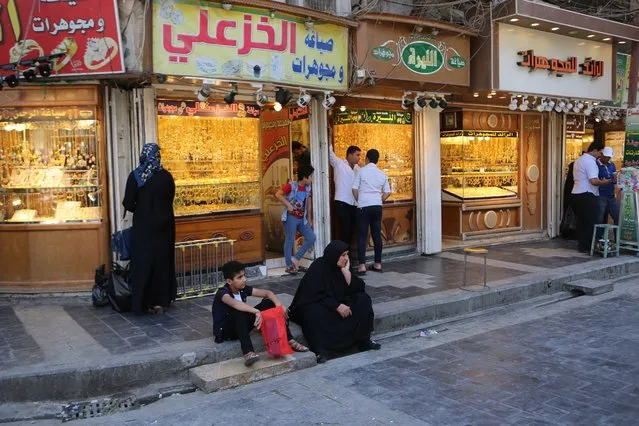 In this Wednesday, May 21, 2019, photo, street vendors and shop owners wait for customers outside the shrine of Imam Moussa al-Kadhim in Kadhimiya district in north Baghdad, Iraq. Many shop owners in the Shiite holy neighborhood of Kadhimiya, have seen their sales drop sharply over the past year since U.S. President Donald began reimposing sanctions on Iran, home to the largest number of Shiite Muslims around the world. (Photo by Khalid Mohammed/AP Photo)
