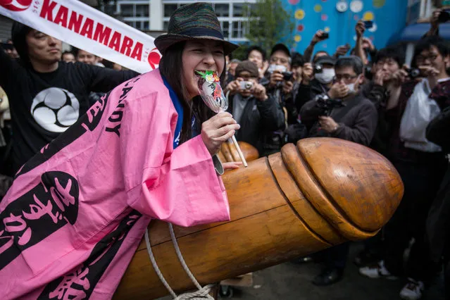 A woman poses for photographers as she sits on a large wooden phallic sculpture during Kanamara Matsuri (Festival of the Steel Phallus) on April 6, 2014 in Kawasaki, Japan. The Kanamara Festival is held annually on the first Sunday of April. The pen*s is the central theme of the festival, focused at the local pen*s-venerating shrine which was once frequented by prostitutes who came to pray for business prosperity and protection against sexually transmitted diseases. (Photo by Chris McGrath/Getty Images)