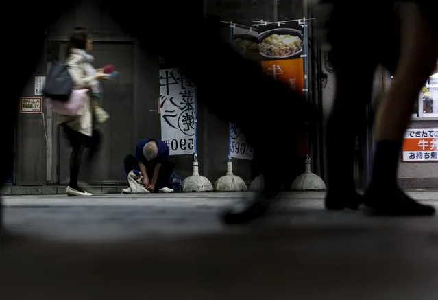 A man sleeps on the side of a street at a business district in Tokyo, Japan, April 30, 2015. (Photo by Yuya Shino/Reuters)