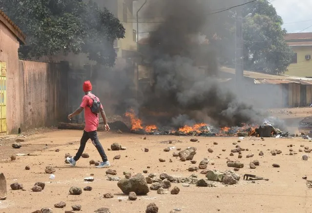 Protesters burn barricades and tires in Conakry street during a demonstration on October 14, 2019 in Guinea. At least one teenager was killed Monday in Conakry, according to a doctor, in clashes in several neighborhoods between security forces massively deployed and thousands of opponents to a third term of the current president Alpha. (Photo by Cellou Binani/AFP Photo)