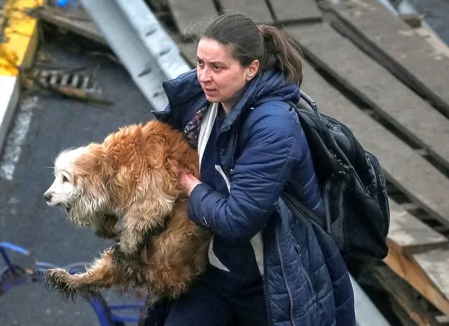 A woman carries her dog during an evacuation, as Russia's invasion of Ukraine continues, in the town of Irpin outside Kyiv, Ukraine on April 1, 2022. (Photo by Gleb Garanich/Reuters)