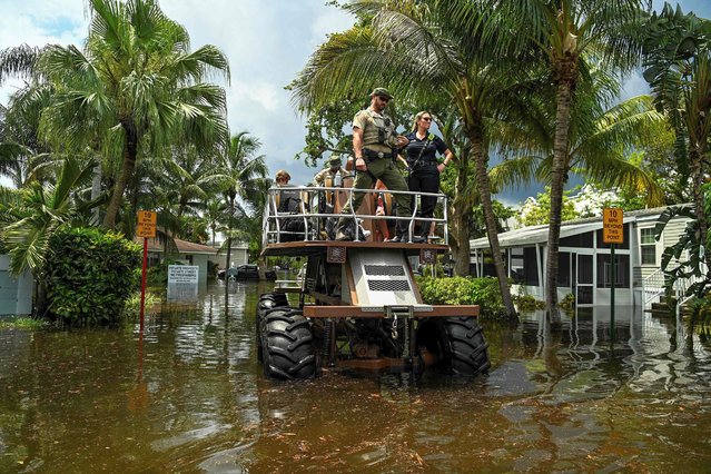 People get rescued by Florida Fish and Wildlife Conservation law enforcement from a flooded neighborhood after heavy rain in Fort Lauderdale, Florida, on April 13, 2023. Torrential rain has drenched much of greater Miami, leaving cars stranded and forcing the closure of schools and Fort Lauderdale's airport until at least Friday. (Photo by Chandan Khanna/AFP Photo)