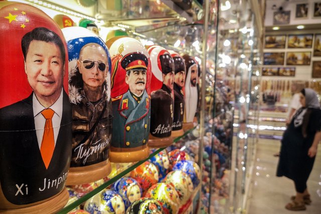 A customer stands next to traditional Russian wooden nesting dolls, Matryoshka dolls, depicting (from L) Chinese counterpart Xi Jinping, Russian President Vladimir Putin and Soviet leader Joseph Stalin at a gift shop at the touristic Arbat street in downtown Moscow on July 22, 2024. Ukrainian foreign minister will visit China on July 23, 2024 for talks on ending Russia's invasion, now in its third year, his ministry announced. China has refused to condemn Russia's invasion and last year released a paper calling for a “political settlement” to the conflict. (Photo by Alexander Nemenov/AFP Photo)