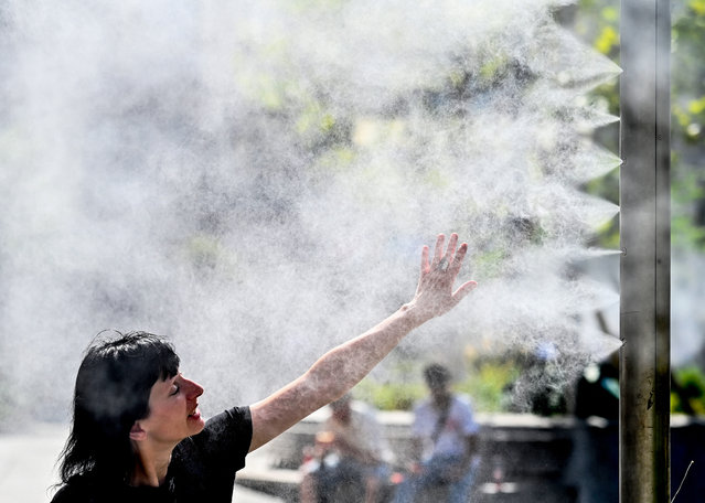 A woman cools down by a water sprayer in Vienna, Austria on a warm September 3, 2024. (Photo by Joe Klamar/AFP Photo)