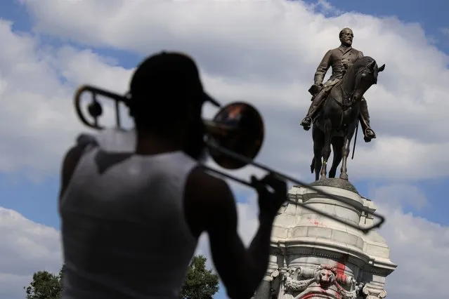 A musician plays trombone near the statue of Robert E. Lee at the Robert E. Lee Memorial on Monument Avenue September 7, 2021 in Richmond, Virginia. The statue, the largest of a Confederate figure remaining in the U.S., is scheduled to be removed tomorrow. (Photo by Alex Wong/Getty Images)