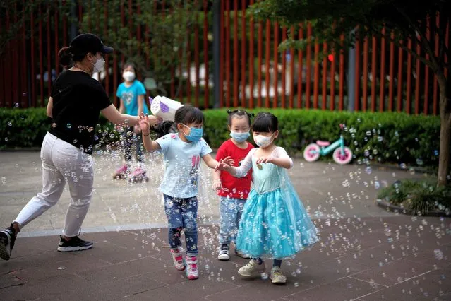 Children wearing protective face masks play amid bubbles at a park, as the city prepares to end the lockdown placed to curb the coronavirus disease (COVID-19) outbreak in Shanghai, China on May 31, 2022. (Photo by Aly Song/Reuters)