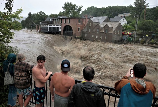 People line the railing over the Ottauquechee River in Quechee, VT on July 10, 2023 to get a closer look as the river rises. (Photo by Jessica Rinaldi/The Boston Globe via Getty Images)