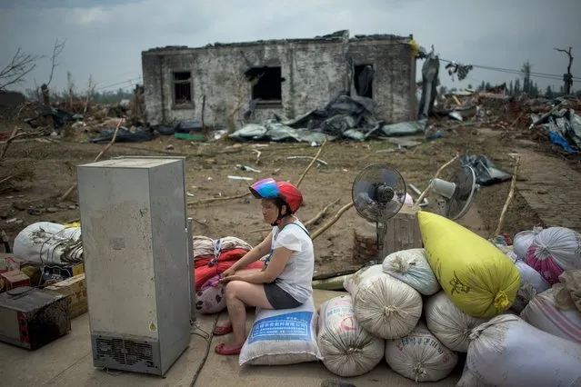 A resident sits in front of a destroyed house after a tornado in Funing, in Yancheng, in China's Jiangsu province on June 24, 2016. Survivors scrabbled through the rubble of their homes on June 24 after hurricane-force winds and a tornado left at least 98 dead in China, with hundreds more injured. Whole villages were levelled and huge trees felled when winds of up to 125 kilometres (77 miles) per hour struck around Yancheng city in the eastern province of Jiangsu on Thursday, the official Xinhua news agency said. (Photo by Johannes Eisele/AFP Photo)