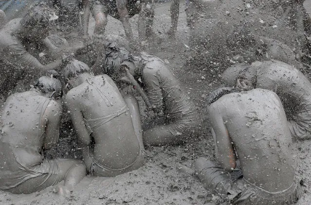 Festival goers wrestle in the mud during the annual Boryeong Mud Festival at Daecheon Beach on July 18, 2014 in Boryeong, South Korea. The mud, which is believed to have beneficial effects on the skin due to its mineral content, is sourced from mud flats near Boryeong and transported to the beach by truck. (Photo by Chung Sung-Jun/Getty Images)