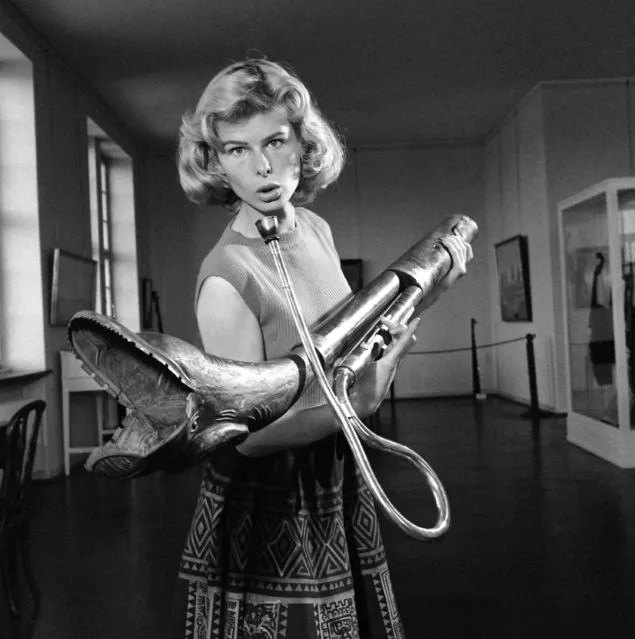 A 19th century horn with a frightening dragon head is held by a model at the exhibition of ancient musical instruments at the municipal museum in Hamburg, June 14, 1957. (Photo by Henry Brueggemann/AP Photo)