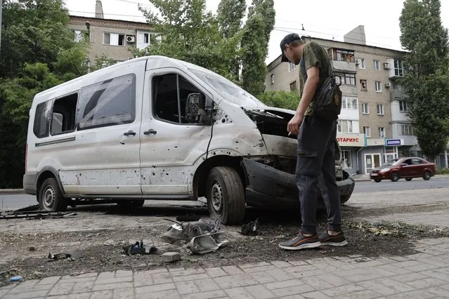 A man inspects a car damaged during shelling in Donetsk, in territory under the government of the Donetsk People's Republic, eastern Ukraine, Wednesday, June 22, 2022. (Photo by Alexei Alexandrov/AP Photo)