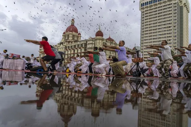 People perform Yoga to mark International Day of Yoga infront of Taj Mahal Palace hotel in Mumbai, India, Tuesday, June 21, 2022. Yoga enthusiasts across the world Tuesday took part in mass yoga events to mark Yoga Day. (Photo by Rafiq Maqbool/AP Photo)