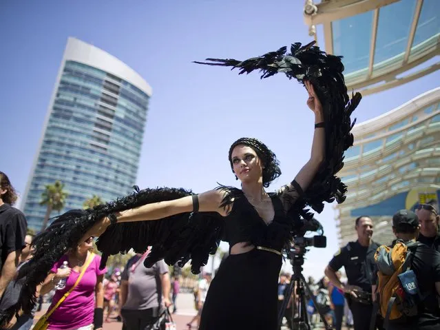 A woman dressed as the character Katniss Everdeen from the movie, “The Hunger Games: Catching Fire”, poses in front of Comic-Con Thursday, July 24, 2014, in San Diego. Thousands of fans with four-day passes to the sold-out pop-culture spectacular flocked to the event Thursday, many clad in costumes. (Photo by AP Photo)