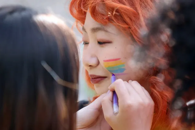 Pride volunteers add rainbow face paint to each other's faces ahead of the Pride in London parade, Saturday, July 2, 2022, marking the 50th Anniversary of the Pride movement in the UK. (Photo by James Manning/PA Wire via AP Photo)