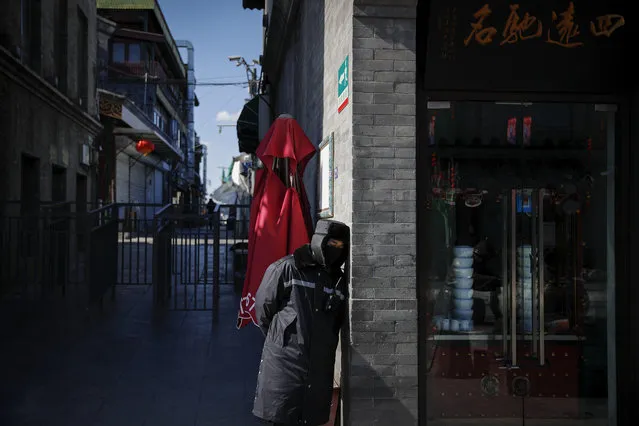 A masked security guard takes a nap next to a closed shop following a COVID-19 virus outbreak, at a quiet main Qianmen Street, a popular tourist spot, in Beijing, Sunday, February 16, 2020. China reported Sunday a drop in new virus cases for the third straight day, as it became apparent that the country's leadership was aware of the potential gravity of the situation well before the alarm was sounded. (Photo by Andy Wong/AP Photo)