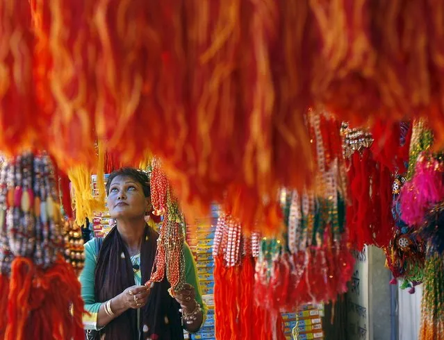 A woman buys “rakhi” or traditional Indian sacred thread, at a stall in a marketplace in Kolkata August 19, 2015. Rakhi is also the name of a Hindu festival, also known as Raksha Bandhan, during which a sister ties one or more of the sacred threads onto her brother's wrist to ask him for her protection. The festival will be celebrated across the country on August 29 this year. (Photo by Rupak De Chowdhuri/Reuters)