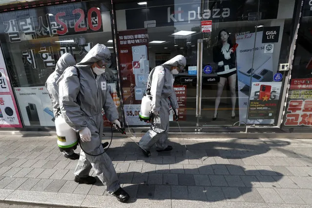 South Korean army soldiers wearing protective gears spray disinfectant as a precaution against the new coronavirus at a shopping street in Seoul, South Korea, Wednesday, March 4, 2020. The coronavirus epidemic shifted increasingly westward toward the Middle East, Europe and the United States on Tuesday, with governments taking emergency steps to ease shortages of masks and other supplies for front-line doctors and nurses. (Photo by Ahn Young-joon/AP Photo)