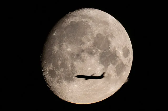 A passenger plane is seen with the full moon behind in Moscow, Russia on August 9, 2022. (Photo by Maxim Shemetov/Reuters)