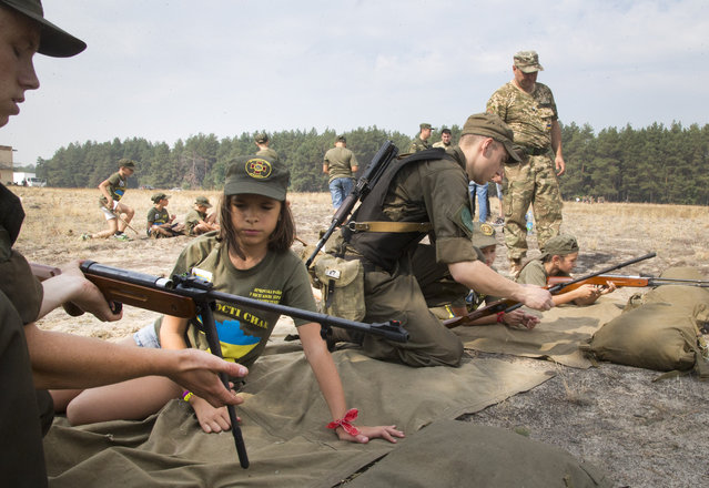 Servicemen teach children to shoot with a rifle at a military training ground of Ukraine's National Guard outside the village of Stare, the Kiev region, Ukraine, Saturday, August 29, 2015. (Photo by Efrem Lukatsky/AP Photo)