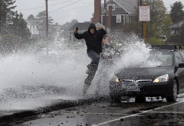 Caleb Lavoie, 17, of Dayton, Maine, front, and Curtis Huard, 16, of Arundel, Maine, leap out of the way as a large wave crashes over a seawall on the Atlantic Ocean during the early stages of Hurricane Sandy, Monday, October 29, 2012, in Kennebunk, Maine. (Photo by Robert F. Bukaty/AP Photo)