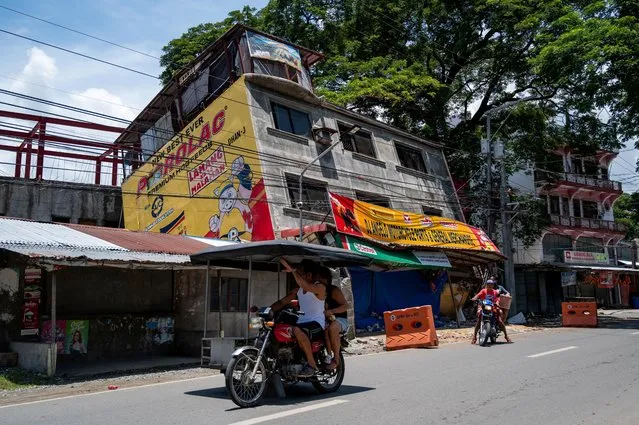 Motorists pass by a damaged building in the aftermath of an earthquake in Bangued, Abra province, Philippines, July 28, 2022. (Photo by Lisa Marie David/Reuters)