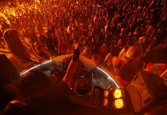 People dance for a DJ at the Dancetronauts mutant vehicle during the Burning Man 2014 “Caravansary” arts and music festival in the Black Rock Desert of Nevada, August 30, 2014. (Photo by Jim Urquhart/Reuters)