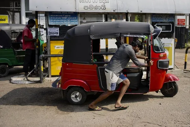 A man pushes his autorickshaw to a fuel station in Colombo, Sri Lanka, Wednesday, July 27, 2022. (Photo by Eranga Jayawardena/AP Photo)