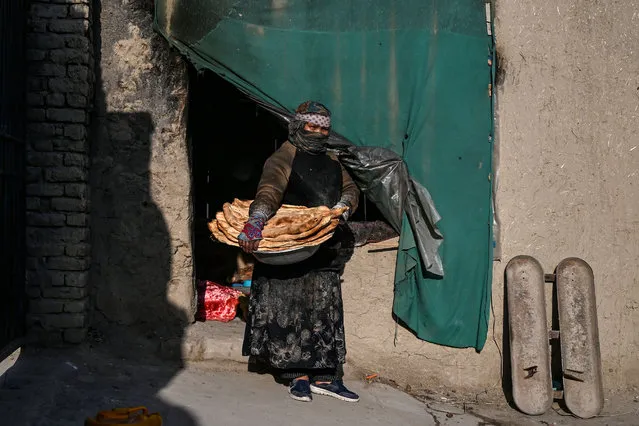 Afghan Zainab Sharifi, 45, baker, poses for a photograph holding loaves of bread outside her bakery in Kabul on April 23, 2020 during the COVID-19 coronavirus pandemic. Ahead of May Day on May 1, 2020, AFP portrayed 55 workers defying the novel coronavirus around the world. Sharifi, a mother of seven, said “hunger will kill my family before the coronavirus if I do not work” as she continues to work at the bakery to support her family and to keep providing her customers. (Photo by Wakil Kohsar/AFP Photo)