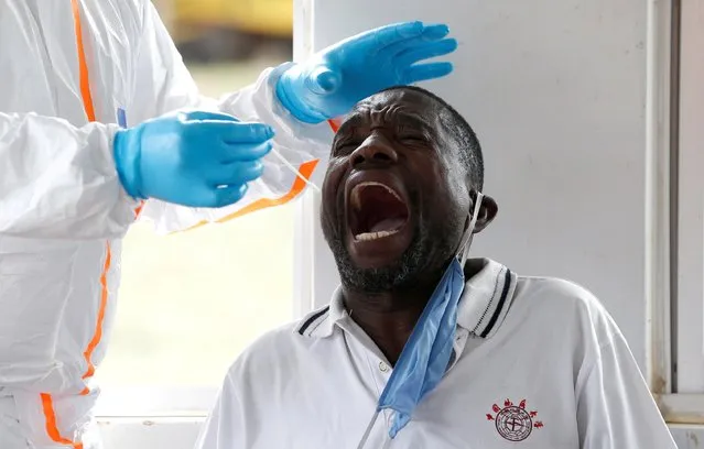 A Kenyan ministry of health medical worker takes a swab from a truck driver during a testing for the coronavirus disease (COVID-19), at the Namanga one stop border crossing point between Kenya and Tanzania, in Namanga, Kenya on May 12, 2020. (Photo by Thomas Mukoya/Reuters)