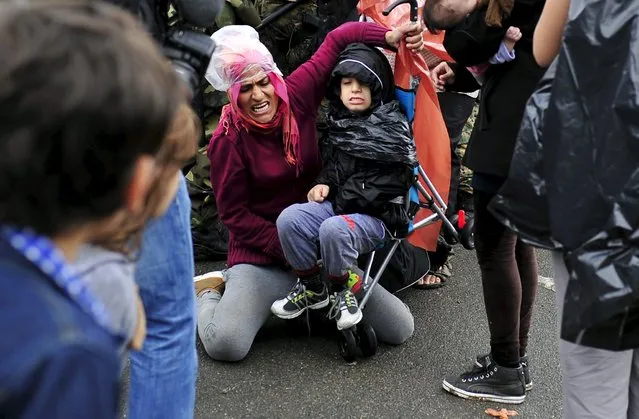 A woman struggles with a child's stroller as a group of immigrants try to pass through police blockades in Gevgelija, Macedonia September 10, 2015. (Photo by Tomislav Georgiev/Reuters)