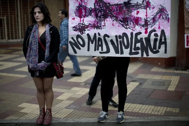 A performer representing a woman attacked by a man stands next to a protester holding a banner that reads in Spanish “No more violence”, during a march against domestic violence in Lima, Peru, Saturday, August 13, 2016. (Photo by Rodrigo Abd/AP Photo)