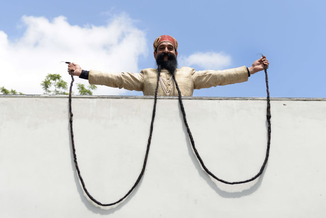 Indian man, Ram Singh Chauhan (61) displays his approximately 18 foot long moustache in Ahmedabad on September 24, 2014.  Ram Singh Chauhan is to be felicitated by the Gujarat Lok Kala Foundation for having the World's Longest Moustache, a feat which has been recognised by the Guinness Book of World Records. (Photo by Sam Panthaky/AFP Photo)