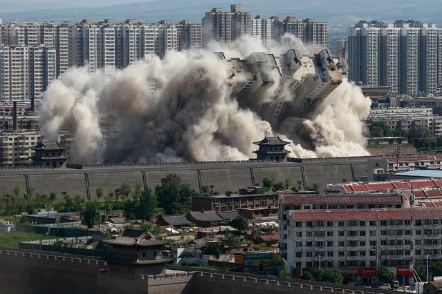 A building crumbles during a controlled demolition conducted to better protect the nearby ancient area of the city in Datong, Shanxi province, China, August 8, 2016. (Photo by Reuters/China Daily)