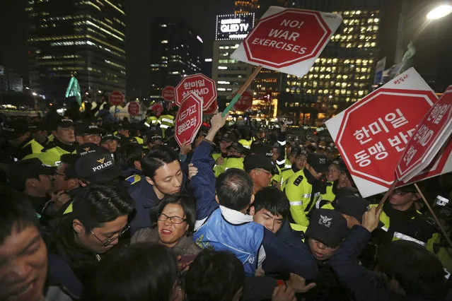 Members of the “No Trump” Coalition struggle with police officers during a rally to oppose a visit by U.S. President Donald Trump in Seoul, South Korea, Tuesday, November 7, 2017. The signs read “Against the US-South Korea-Japan alliance”. (Photo by Ahn Young-joon/AP Photo)