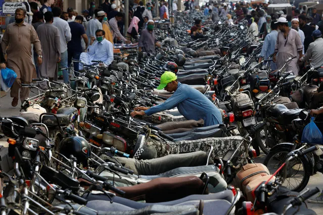 A boy parks his motorcycle amid hundreds of others outside a shopping bazar, after Pakistan started easing the lockdown as the spread of the coronavirus disease (COVID-19) continues, in Karachi, Pakistan on May 12, 2020. (Photo by Akhtar Soomro/Reuters)