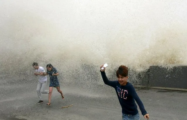 Visitors run away from a wave caused by a tidal bore which surged past a barrier on the banks of Qiantang River, in Hangzhou, Zhejiang province, China, September 15, 2015. (Photo by Reuters/China Daily)