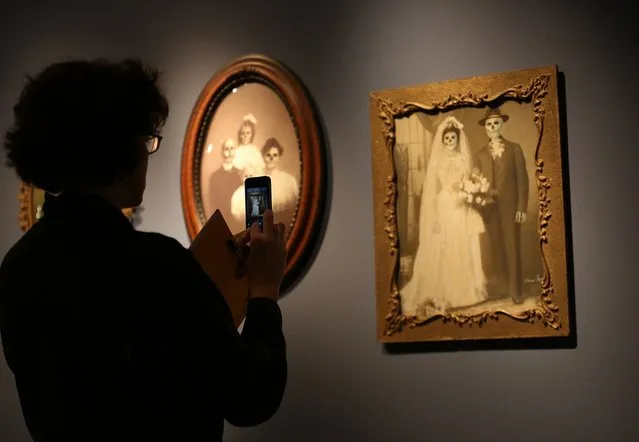 A visitor photographs a work by Mexican artist Marcos Raya called Family Portrait : Wedding at the “Death: A Self-portrait” exhibition at the Wellcome Collection on November 14, 2012 in London, England. The exhibition showcases 300 works from a unique collection by Richard Harris, a former antique print dealer from Chicago, devoted to the iconography of death. The display highlights art works, historical artifacts, anatomical illustrations and ephemera from around the world and opens on November 15, 2012 until February 24, 2013. (Photo by Peter Macdiarmid)