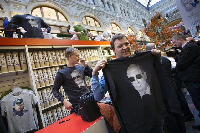 People choose shirts bearing an image of Russian President Vladimir Putin at GUM (the State Department Store) in Moscow, Russia, Monday, October 6, 2014. Souvenirs and clothing featuring Putin or pro-government slogans have become popular in Russia this year. (Photo by Alexander Zemlianichenko/AP Photo)