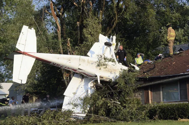 In this Thursday, August 25, 2016 photo, rescue personnel help at the scene where a small plane crashed into a house a few miles north of Terre Haute, Ind., near Sky King Airport. Authorities say two people were rescued from the plane wreckage and flown to a hospital. A resident says no one was inside the house when the plane struck. (Photo by Jim Avelis/The Tribune-Star via AP Photo)