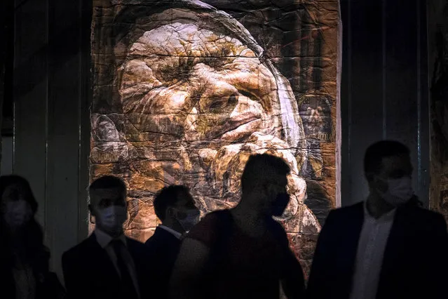 People, some wearing face masks for protection against COVID-19 infections, are silhouetted against large artworks by Bosnia's best-known living painter, Safet Zec, during the opening of his exhibition in Potocari, Bosnia, Tuesday, July 7, 2020. The exhibition, dedicated to the more than 8,000 Muslim Bosniak men and boys who perished 25 years ago during 10 days of slaughter after Srebrenica was overrun by Bosnian Serb forces on July 11, 1995, opened in the infamous factory which housed the U.N. peacekeepers' compound during Bosnia's 1992-95 war. (Photo by Kemal Softic/AP Photo)